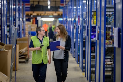 Two workers walking in a warehouse discussing logistics for the material handling industry. 